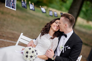 Happy bride and groom sitting on bench in the park