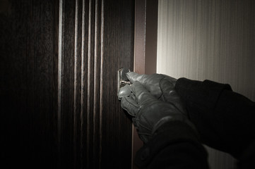 man's hand in a glove opening the door