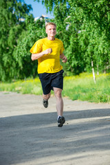 Sporty man jogging in city street park. Outdoor fitness.