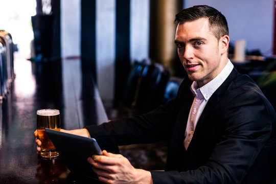 Businessman using tablet having a beer