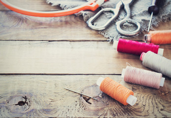 Scissors, bobbins with thread and needles, striped fabric. Old sewing tools on the old wooden...