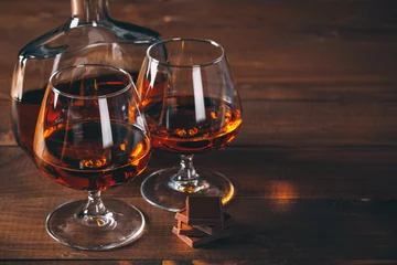Gardinen Two glasses of cognac and bottle on the wooden table. © Ievgenii Meyer