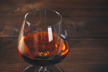 Glass of cognac on the wooden table.