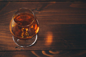 Glass of cognac on the wooden table.