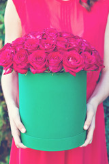 Bouquet of red roses in a box  in the hands of the girl.