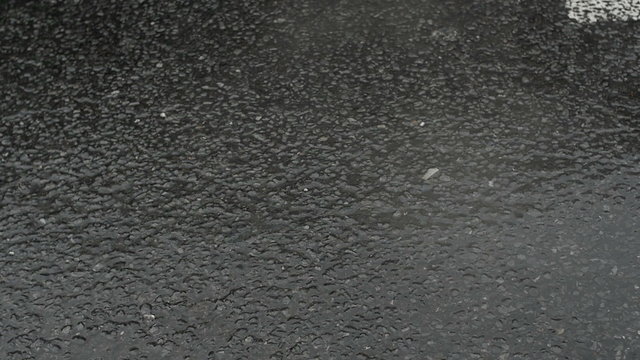 Slow motion of raindrops and steam on the pavement.