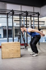 Muscular man jumping on wooden block