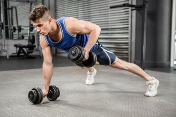 Obraz na płótnie Canvas Muscular man doing push up with dumbbells