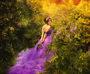 Fashion portrait of young beautiful pretty girl posing against lilac bushes in blossom © olenakucher
