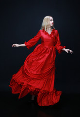 full length portrait of a beautiful blonde woman wearing a historical red silk, victorian era ball gown.