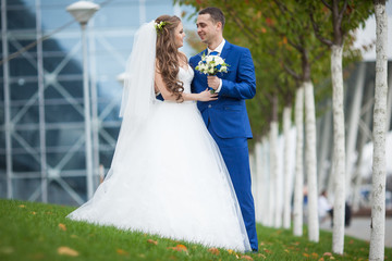 gorgeous happy brunette bride and elegant groom in blue suit on