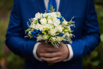 gorgeous elegant groom in blue suit holding stunning stylish bou
