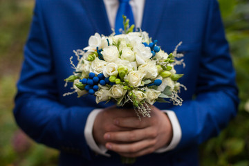 gorgeous elegant groom in blue suit holding stunning stylish bou