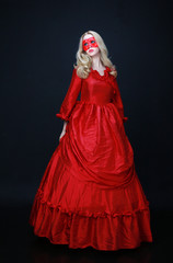 full length portrait of a beautiful blonde woman wearing a historical red silk, victorian era ball gown.