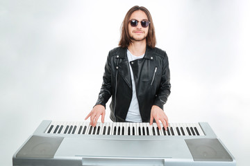 Smiling man with long hair in sunglasses playing on synthesizer