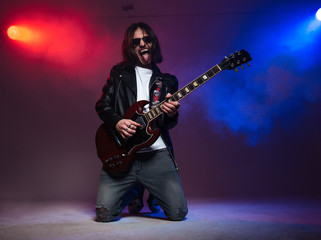 Fototapeta premium Crazy young guitarist playing electric guitar and shoing tongue