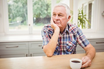 Thoughtful senior man sitting at table