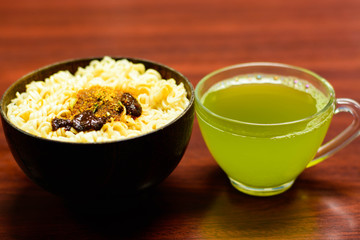 cups of green tea and noodles on wooden table