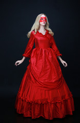 full length portrait of a beautiful blonde woman wearing a historical red silk, victorian era ball gown.
