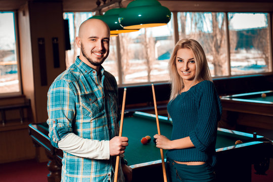 Cute young couple plays billiard and having some fun