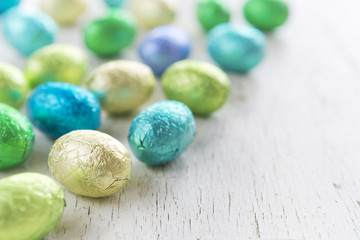 Small chocolate Easter eggs on a rustic white background