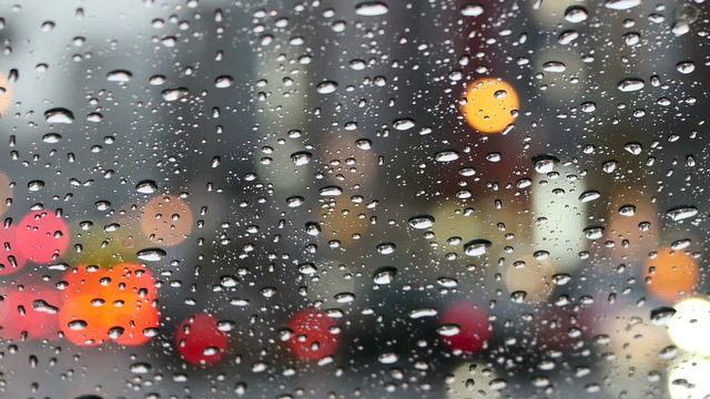 Raindrops on the windshield, and defocused commuters with umbrellas.
