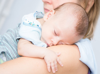 Cute baby sleeping on his mother's shoulder