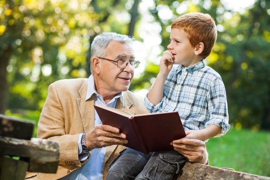 Grandfather and grandson are reading book and learning about nature