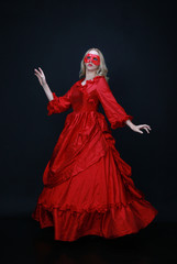 Naklejka premium full length portrait of a beautiful blonde woman wearing a historical red silk, victorian era ball gown.