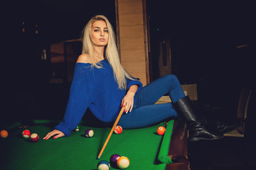 Gorgeous blonde lady plays billiard on the pool table