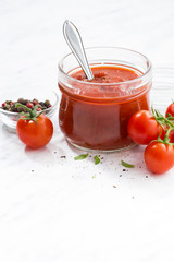 tomato sauce in a glass jar and white background, vertical