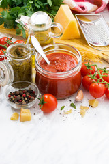 tomato sauce, pesto and ingredients for pasta on a white table