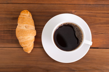 Cup of coffee on the table croissant. Top view .