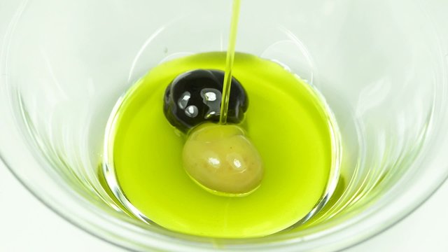 Olivenöl läuft in eine Glasschüssel
