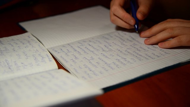  boy writes in notebook homework on Russian language