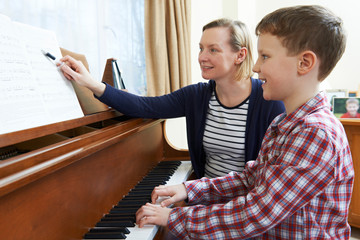 Obrazy na Plexi  Chłopiec z nauczycielem muzyki ma lekcję gry na pianinie