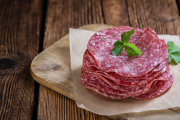 Old wooden table with sliced Salami