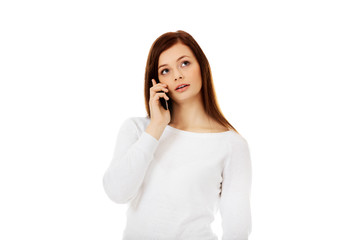 Thoughtful teen woman talking through a mobile phone