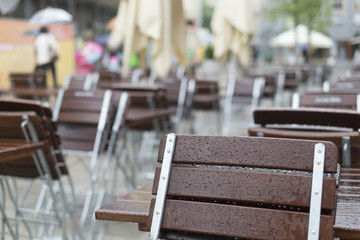 Leere Tische und Bänke eines Restaurant bei Regen