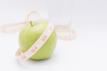 A green apple with a measuring tape wrapped around it for the co