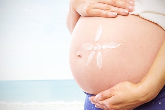 Composite image of pregnant woman with cream on bump