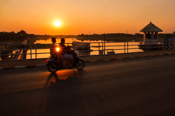 Silhouette of motorcycle on the water dam at sunset.