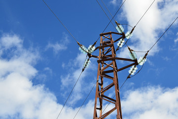 Detail of an Old Rusty Electric Pole on Blue Sky with Fluffy White Clouds