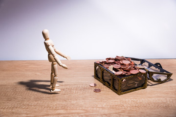 A wooden doll man with his savings, gold coin. All composed with thai baht twenty-five cent, fifty cent, thai baht and yuan 