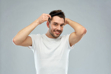 happy man brushing hair with comb over gray