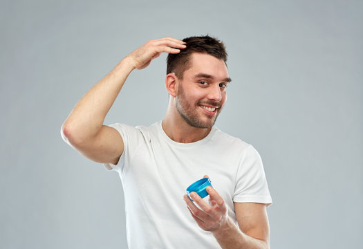 happy young man styling his hair with wax or gel