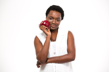 Beautiful smiling african american woman standing and holding red apple