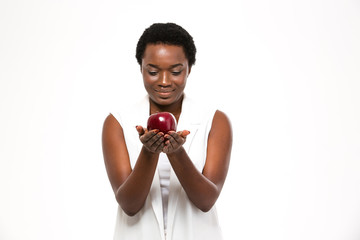 Attractive cheerful african woman holding big red apple on palms