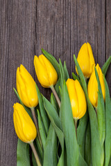 Yellow tulips on wooden background. Top view