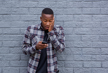 African man looking surprised while reading a text message